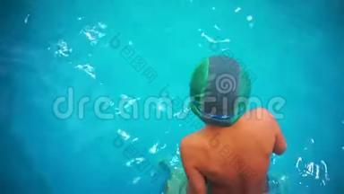 一个小男孩在游泳池里学游泳，俯视，他跳进水里。